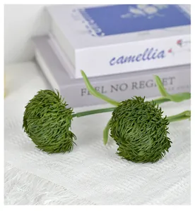 Detalle de bola de musgo de clavel artificial sobre mantel de flecos blancos
