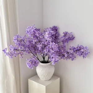 Lush purple artificial lilac flowers in a white wavy ceramic vase for home decor