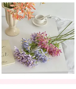 Detail of purple artificial Agapanthus flowers on white desk with decor books