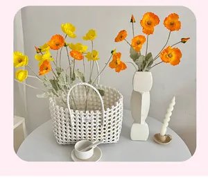 Handwoven white plastic storage basket with double handles and vibrant artificial poppy flowers