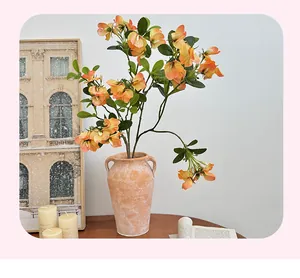 Detailed view of orange sweet pea flowers in a rustic ceramic vase for home decor