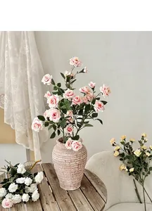 Primo piano di rose rosa in un vaso di ceramica testurizzato su un tavolo di legno