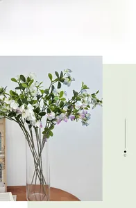 Detail of lifelike artificial sweet pea flowers in a glass vase on a wooden table