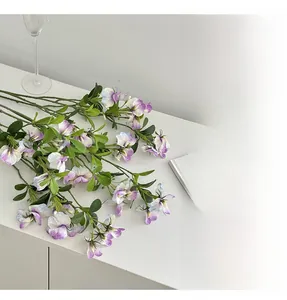 Close-up of lifelike purple and white gradient sweet pea flowers on a white table