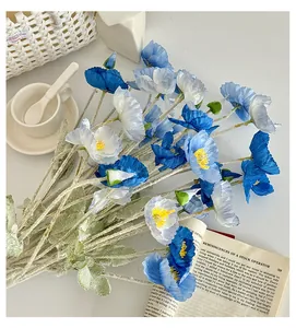 Close-up of artificial silk poppies in blue and white with realistic flocked stems in a basket