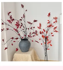 Detailed close-up of artificial red berries in a textured ceramic vase for home decor