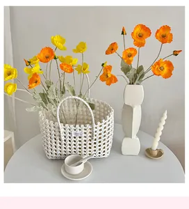 White woven basket bag used as a vase for vibrant artificial poppy flowers home decor