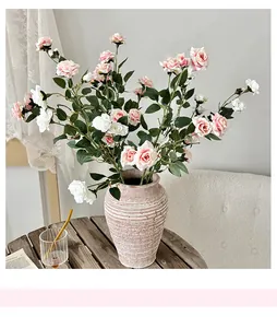 Detalle de rosas artificiales rosas y blancas en un jarrón sobre mesa de madera