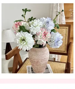 Macro detail of artificial peony bouquet in a textured ceramic vase on a vintage chair