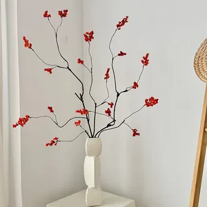 Artificial red holly berry stems in modern white geometric ceramic vase for home decor