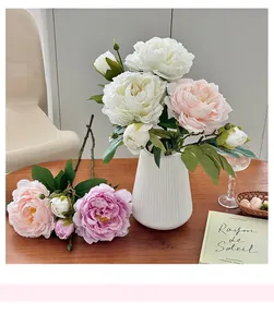 Bouquet de pivoines artificielles dans un vase en céramique blanche sur table en bois