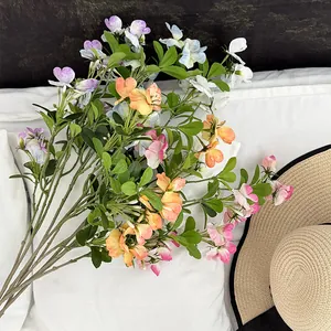Artificial sweet pea bouquet in assorted colors on white fabric with a straw hat decor