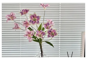 Bouquet di gigli artificiali con petali rosa e foglie verdi in vaso di vetro