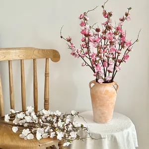 Artificial plum blossom branches in pink and white set in a ceramic vase for home decor