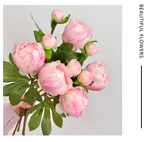 Dettaglio di un bouquet di peonie di seta rosa con fiori aperti e foglie verdi realistiche