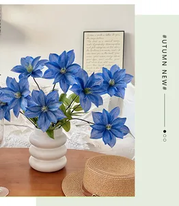 Fiori di clematide blu in un vaso di ceramica a onde su un tavolo di legno di casa