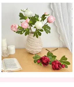 Dettaglio macro di fiori di pioni finti in seta rosa con foglie verdi in un vaso elegante