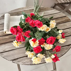 Ramo de rosas artificiales rojo oscuro y crema sobre una mesa de madera con libro