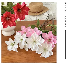 Composizione artistica di fiori di clematide artificiali in rosso, rosa e bianco su legno