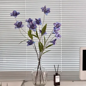 Gigli viola artificiali in un vaso di vetro per decorazioni di casa e matrimoni