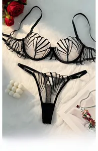 Flat lay of sheer embroidered lace lingerie set with roses and pearls for romantic mood