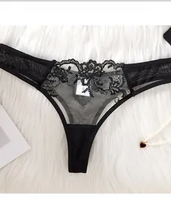 Détail de string en dentelle noire avec broderie florale et tulle sur peluche blanche