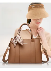 Close-up of brown textured leather handbag with decorative printed silk scarf and gold hardware
