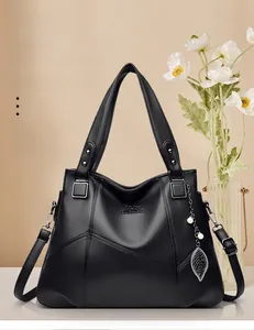 Detailed view of black pebbled leather tote with kangaroo logo and decorative leaf pendant