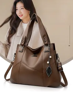 Detail of brown litchi pattern leather tote bag featuring a metal kangaroo logo and leaf pendant