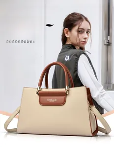 Détail du sac à main en cuir beige et marron avec texte embossé et poignées de transport