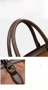 Detailed view of brown crocodile texture leather and reinforced metal hardware on the tote