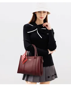 Detail of burgundy leather tote with pebble texture and decorative silk scarf detail