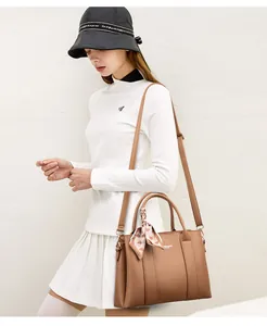 Close-up of brown textured leather tote bag with heart pattern scarf and logo detail