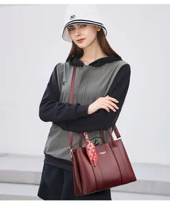 Detail of burgundy lychee grain leather handbag with decorative silk scarf on handle
