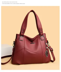 Detailed macro view of burgundy lychee grain leather handbag with silver leaf pendant