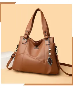 Detail of dark brown lychee textured leather tote with kangaroo logo and leaf pendant