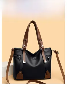 Detail of lychee pattern leather texture and brand logo on a black and brown tote bag