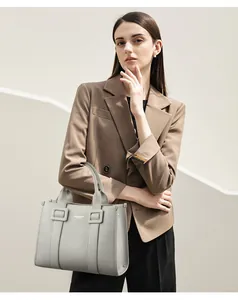 Detailopname van grijze shopper van generfd leer met vierkante gespen en handgrepen