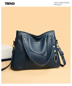 Detail of blue pebbled leather tote bag with silver logo and decorative leaf pendant