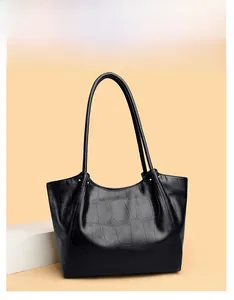Detail of black faux crocodile skin tote bag texture on a white geometric stand