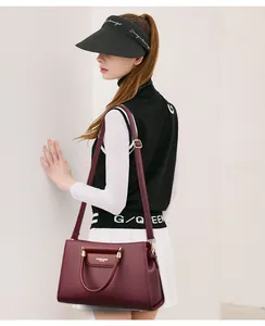 Détail d'un sac à main en cuir bordeaux avec texture grainée et finitions dorées élégantes