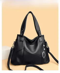 Detailed close-up of black lychee grain leather tote with leaf pendant and kangaroo logo