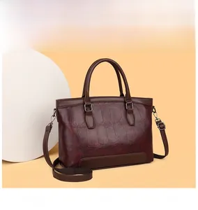 Detail of burgundy crocodile-embossed leather handbag with dual handles and strap