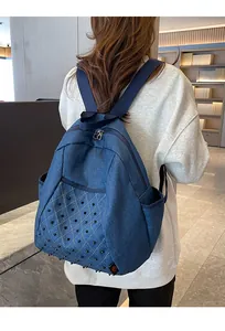 Detail of blue denim backpack with punk rivets and white diamond stitching patterns
