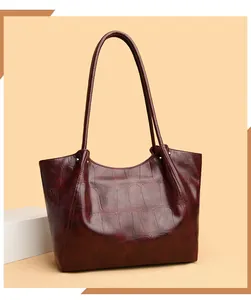 Close-up of deep burgundy tote bag with embossed crocodile texture and leather straps