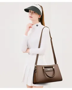 Sac bandoulière en cuir grainé marron porté avec une bandoulière réglable chic