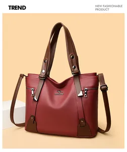 Detail of red textured leather handbag with silver kangaroo logo and brown straps