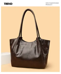 Detail of dark brown faux crocodile leather tote bag with elegant glossy textured finish