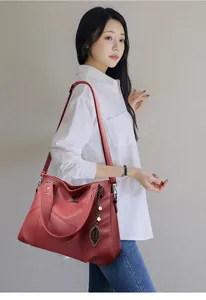 Detail of burgundy pebbled leather tote bag with leaf charm and kangaroo metal logo