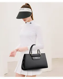 Gros plan détaillé d'un sac à main en cuir noir avec grain litchi et détails dorés